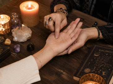 Palm reader examining a person’s hand during a mystical palmistry reading.